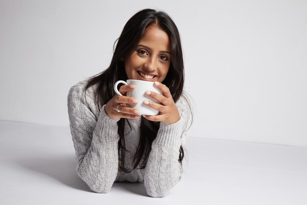 Woman with a cup of hot dring lies on the floor