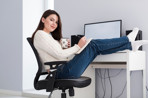 Woman with cup and pen at computer