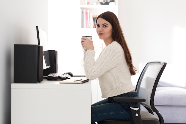 Free photo woman with cup sitting at table