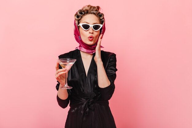 woman with curlers in surprise poses on pink wall