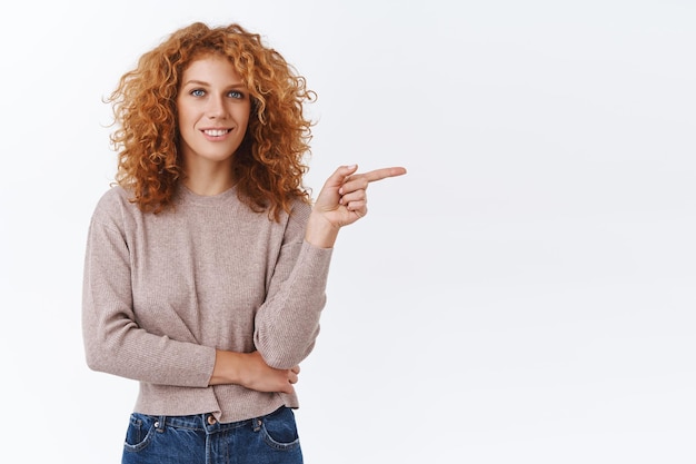 woman with curly hair in blouse, pointing right and smiling on white