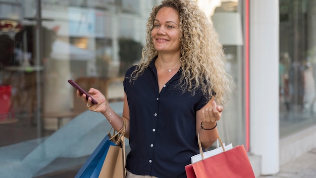 Donna con capelli ricci che trasportano borse della spesa