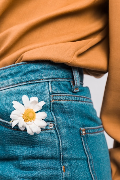 Woman with daisy flower in jeans pocket