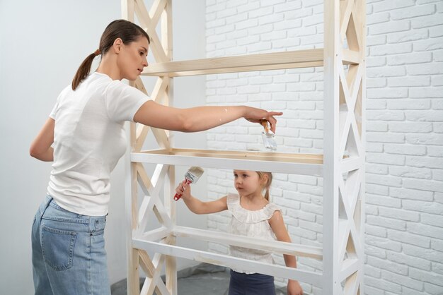 Woman with daughter painting wooden rack