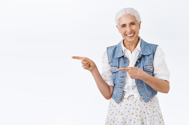 woman with denim vest, dress, pointing fingers left, indicating promo copy space, smiling happy and look camera as give advice, recommend product