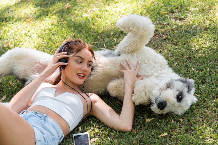 無料Photo 犬の屋外リスニング音楽を持つ女性
