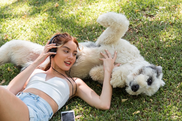 犬の屋外リスニング音楽を持つ女性