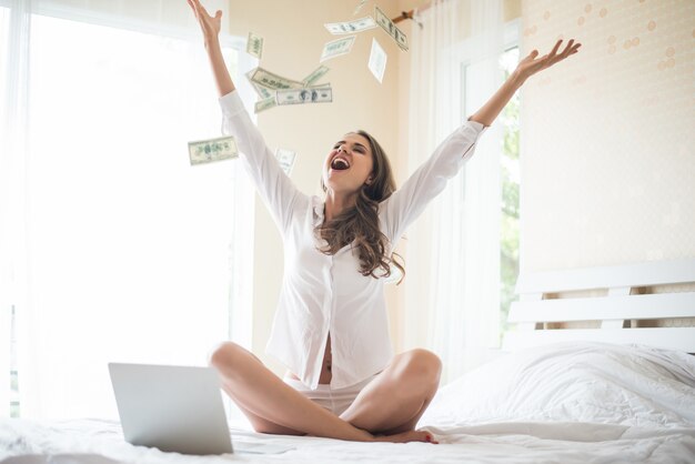ベッドの上のドル紙幣を持つ女性