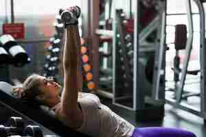 Foto gratuita donna con dumbbells sdraiato sulla panchina