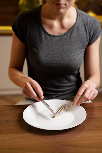 Free photo woman with eating disorder having a pea on her plate