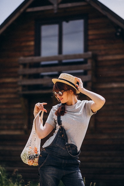Foto gratuita donna con la borsa di eco con frutta in una campagna