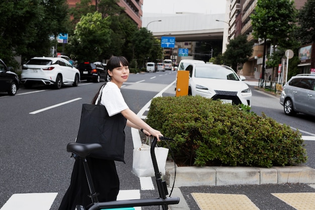 市内の電動自転車を持つ女性