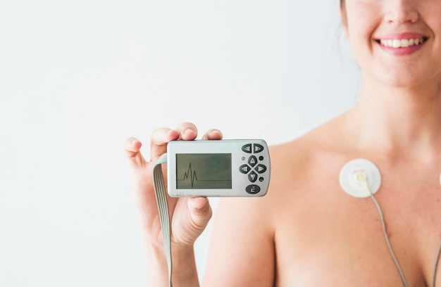 Woman with electrodes holding monitor with cardiogram