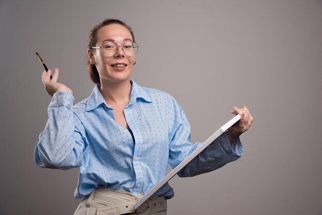 Woman with empty canvas and brush on gray