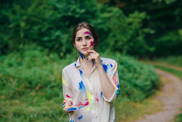 Woman with face and clothes stained paint with pensive face