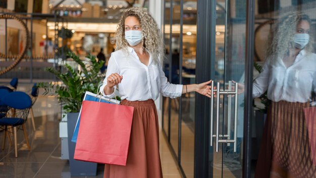 買い物袋を運ぶフェイスマスクを持つ女性