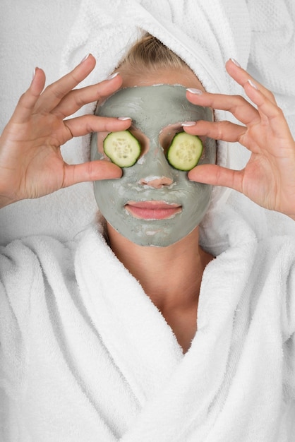 Foto gratuita donna con maschera facciale e fette di cetriolo