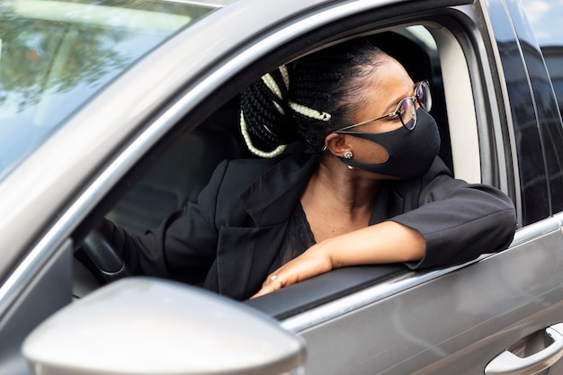 Женщина с маской для лица, глядя назад во время вождения своей машины