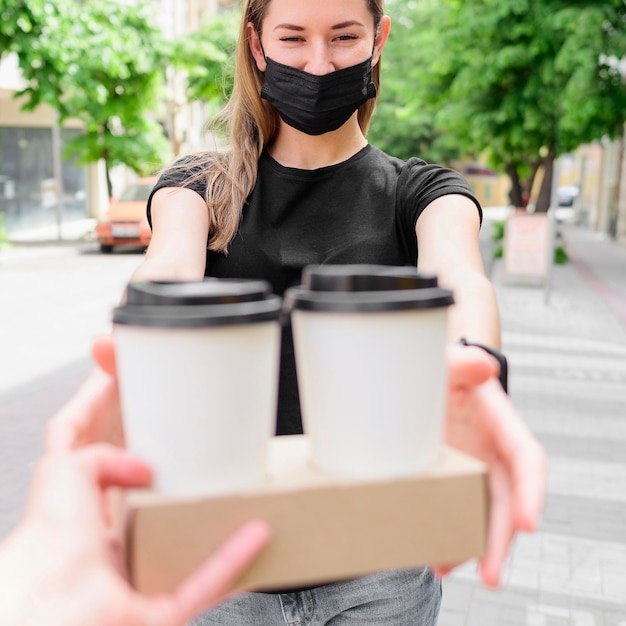 Woman with face mask receiving hot drinks