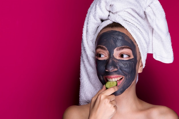 Woman with face mask tasting cucumber