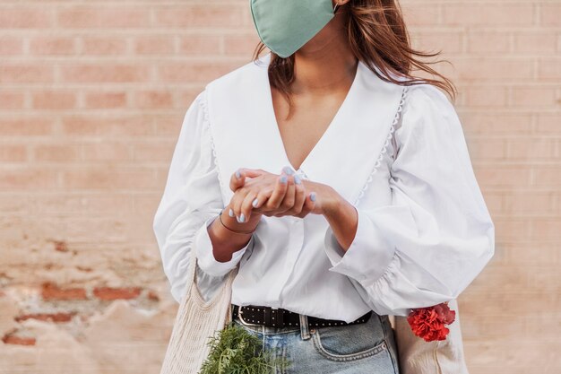 Woman with face mask using hand sanitizer