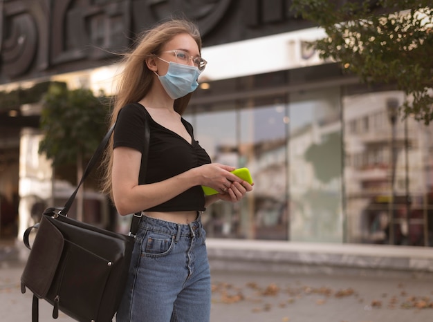 街を歩いているフェイスマスクを持つ女性