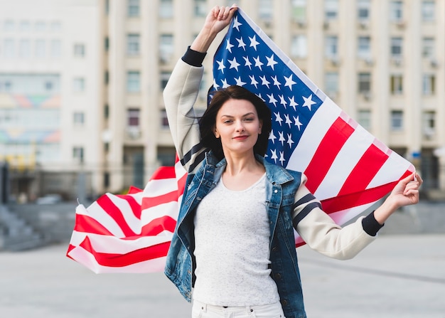 路上でアメリカ合衆国の旗を持つ女性