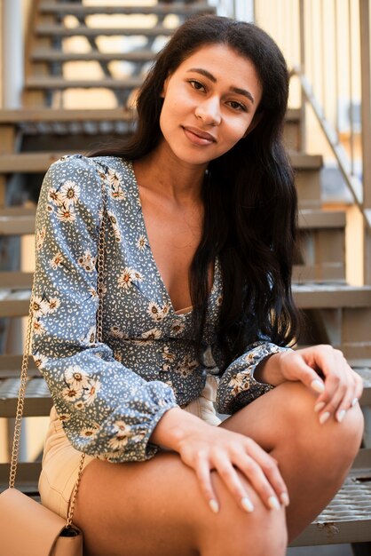 Woman with floral shirt sitting on stairs and looking at camera