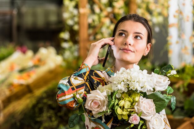 電話で話している花の花束を持つ女性