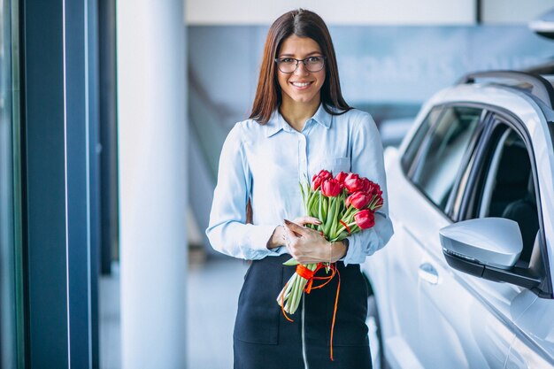 Woman with flowers in a car showroom