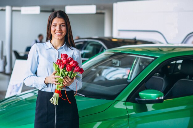 Woman with flowers in a car showroom