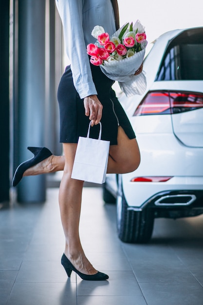 Woman with flowers in a car showroom