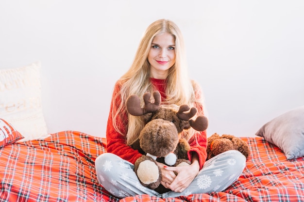 Free photo woman with fluffy toy deer on bed