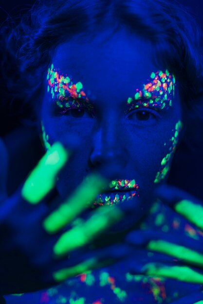 Женщина с флуоресцентным макияжем на лице и руке