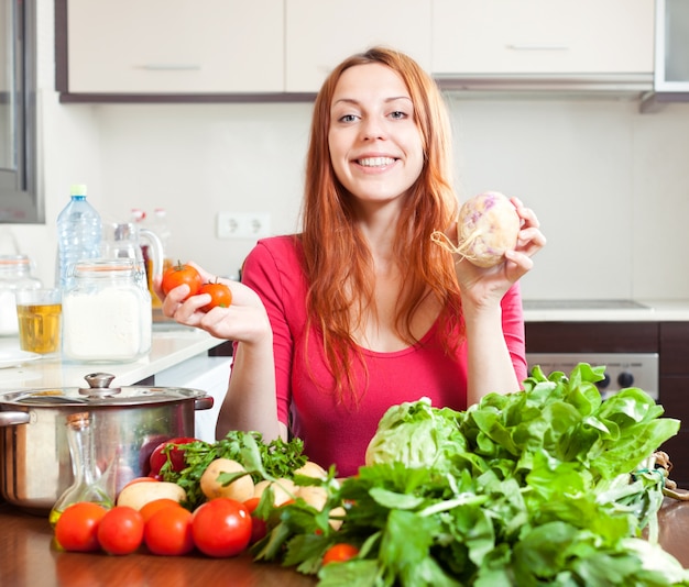 Женщина со свежими овощами в кухне