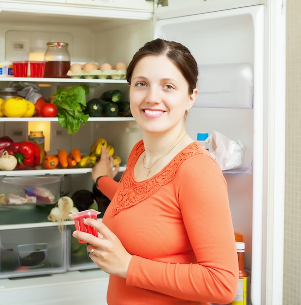 Free photo woman with fruits jam near fridge