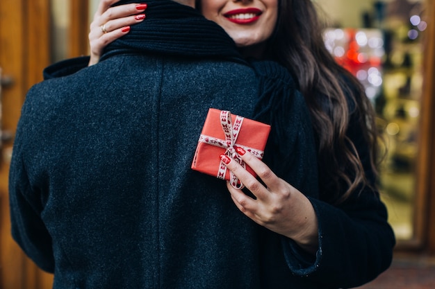 Woman with gift box embracing man