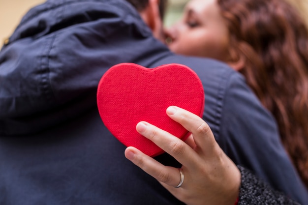 Woman with gift box in heart shape hugging man