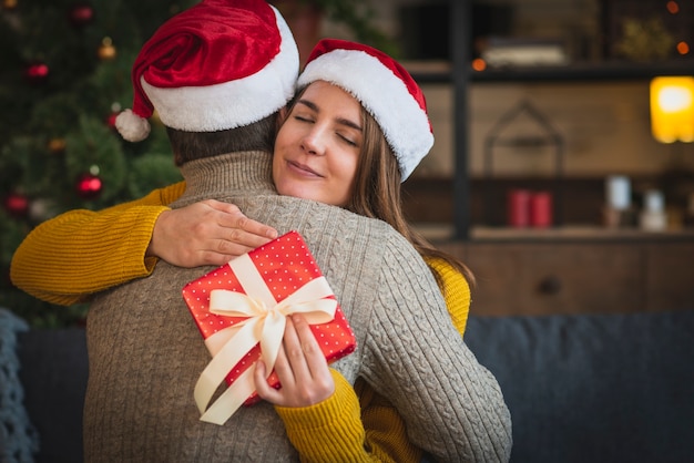 Woman with gift hugging man