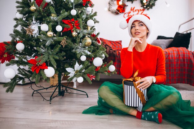 Woman with gifts by Christmas tree