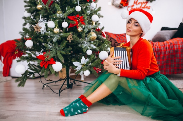 Woman with gifts by Christmas tree
