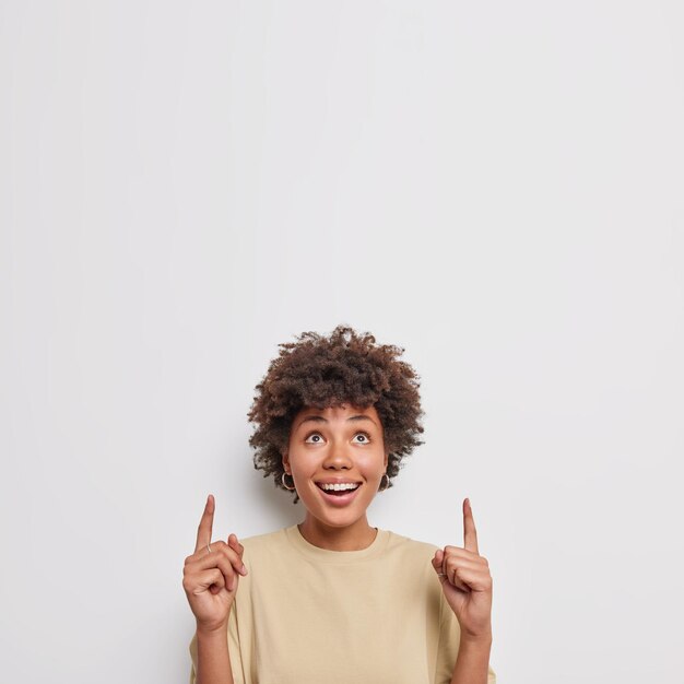 woman with glad expression has unbelievable gaze dressed in casual clothes isolated on white. Wow what great offer for you.