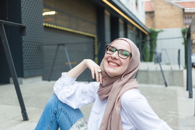 Woman with glasses and hijab smiling