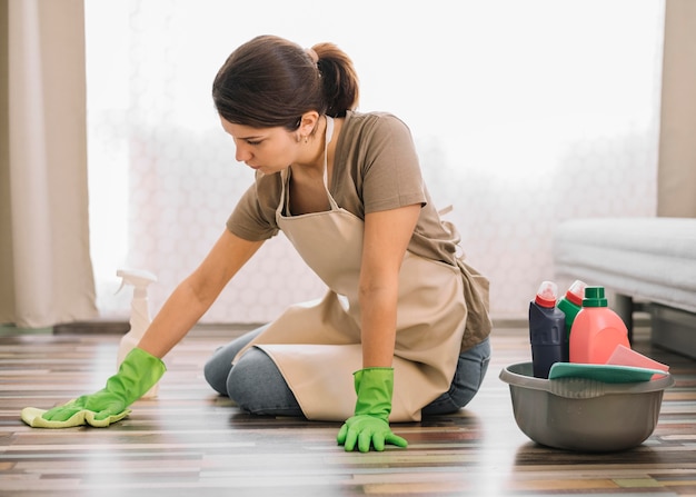 床を掃除して手袋を持つ女性