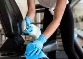 Free photo woman with gloves cleaning gym equipment