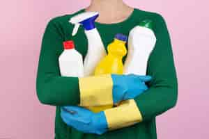 Free photo woman with green sweater hugging many cleaning products in her arms