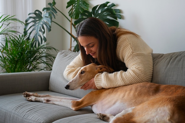 Woman with greyhound dog at home on the couch