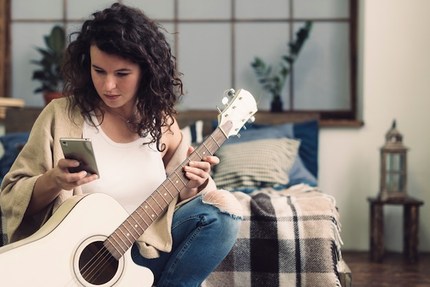 Бесплатное фото Женщина с гитарой и смартфоном