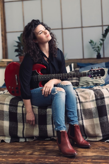 Free photo woman with guitar in her room