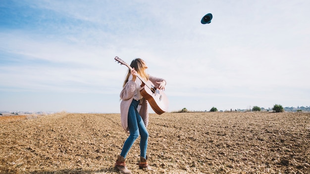 Free photo woman with guitar looking at hat